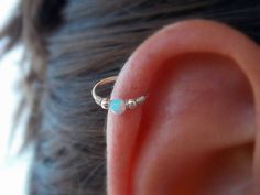 a woman's ear with a single opal in the middle and two smaller opals on each side