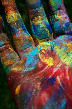 a person's hand covered in multicolored paint