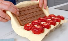 a person placing strawberries on top of a chocolate bar