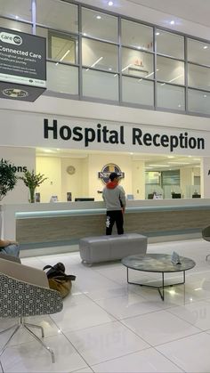 a man standing in front of a hospital reception counter with chairs and tables around it