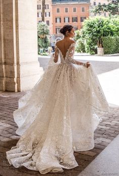 a woman in a wedding dress is standing on the sidewalk with her back to the camera