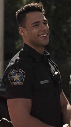 a smiling police officer standing in front of a car