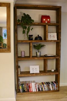 a bookshelf filled with lots of books next to a mirror on the wall