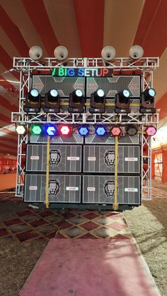 an outdoor stage set up with lights and sound equipment on it's sides, in front of a large tent