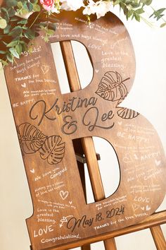 a wooden easel with writing on it and flowers in the vase next to it