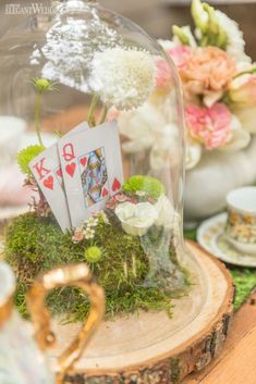 a glass cloche with flowers and cards in it sitting on a table next to other items