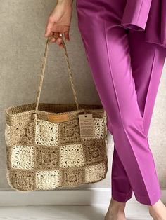 a woman in pink pants and heels holding a woven bag with handles on both sides