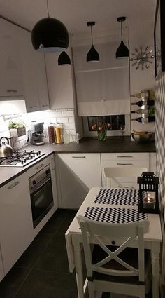 a kitchen with white cabinets, black and white checkerboard table cloth on the floor