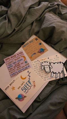 two cards with sheep on them laying on a bed next to each other and some writing