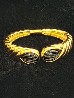 "This elegant Kenneth J Lane bracelet is from the 1990's and is in mint condition.  The bracelet is a hinged cuff style and is ribbed with 2 ribbed  black cabochons.  The \"KJL\" signature stamp is marked clearly for authenticity.  The bracelet measures 2 1/4\" inside side to side fully closed and easily expands.  It measures 1 1/4\" from hinge to the front opening.  This is a very timeless classic style that is a great addition to any jewelry collection." Adjustable Retro Gold Bangle, Retro Gold Bangle Cuff Bracelet, Retro Adjustable Gold Bangle, Antique Gold Hinged Cuff Bracelet, Luxury Antique Hinged Jewelry, Vintage Hinged Cuff Bracelet, Vintage Collectible Cuff Bangle Bracelet, Vintage Hinged Bracelet, Vintage Black Bangle Cuff Bracelet