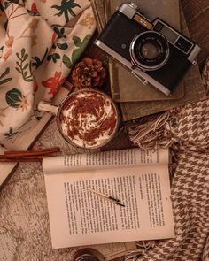 an old book, camera, and cup of coffee are on the table next to some books