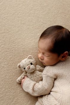 a baby is sleeping with a teddy bear on the floor in front of it's face