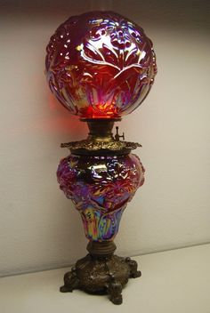 a colorful glass lamp sitting on top of a white table next to a light bulb