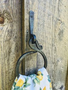 a towel hanging from a hook on a wooden door with a lemon print cloth covering it