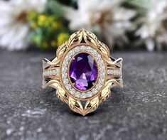 an oval shaped amethorate and diamond ring on a table with flowers in the background