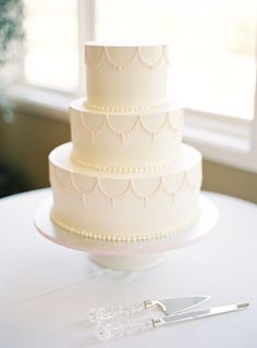 a three tiered wedding cake sitting on top of a table next to a pair of scissors