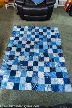 a blue and white patchwork quilt on the floor in a living room with a black chair