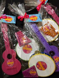 several colorful musical instruments in plastic bags on a black surface with red ribbon around them