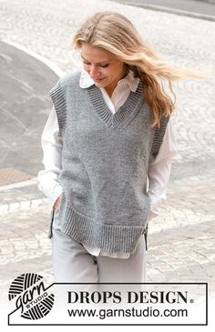 a woman walking down the street wearing a gray sweater vest and white collared shirt