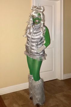 a woman dressed in silver and green standing next to a door