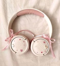 hello kitty headphones laying on top of a white sheet with pink ribbon around the ears