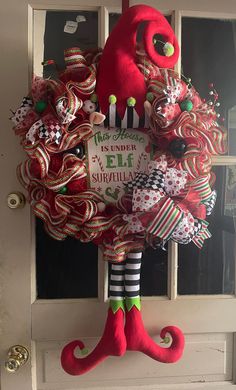 a christmas wreath hanging on the front door decorated with candy canes and stockings,