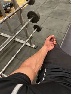 a man sitting on top of a bench next to a barbell rack in a gym