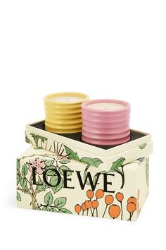 three candles sitting in a box with flowers on the front and one is pink, yellow and