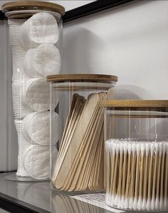 several plastic containers with wooden spoons in them on a shelf next to a mirror