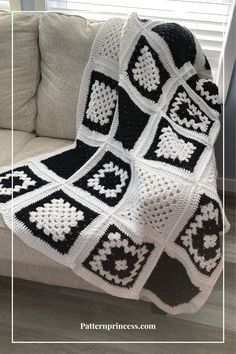 a black and white crocheted blanket sitting on top of a couch next to a window