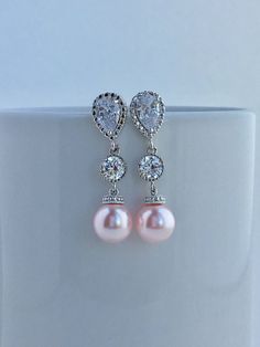 Classic cubic zirconia and pearl bridal drop earrings in rhodium plated brass setting. Earrings feature clear cubic zirconia teardrop ear post with cubic zirconia connector and 10mm Swarovski pink pearl dangle drops. Total length of the earring is 3.5 cms. For matching necklace click: https://www.etsy.com/listing/518298752/pink-pearl-bridal-necklace-blush-pink?ref=shop_home_active_2 For complete set click: https://www.etsy.com/listing/518297586/pink-pearl-bridal-earrings-blush-pink?ref=listing-s Pink Teardrop Pearl Earrings For Wedding, Pink Pearl Drop Bridal Earrings For Wedding, Classic Pink Pearl Earrings For Wedding, Classic Pink Pearl Wedding Earrings, Classic Pink Earrings For Wedding, Silver Pearl Drop Earrings For Bridal Shower, Elegant Pink Cubic Zirconia Bridal Earrings, Pink Pearl Bridal Earrings For Wedding, Pink Pearl Earrings For Wedding