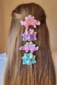 the back of a woman's head with three crocheted hair clips in different colors