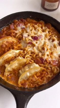 an iron skillet filled with pasta and sauce on top of a white countertop