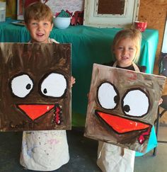 two children are holding paintings made to look like faces