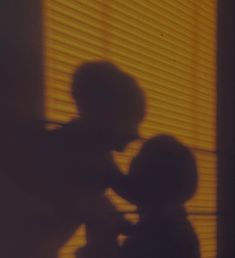 the shadow of a child's head and arm on a window sill with blinds