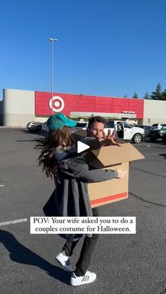 a man is holding a cardboard box in the middle of a parking lot with his arms outstretched