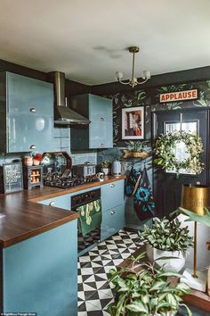 a kitchen with blue cabinets and green plants on the counter top, along with a checkered floor