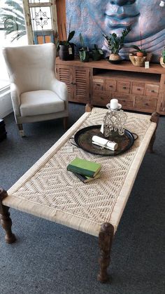 a living room with a coffee table and two chairs in front of a large painting