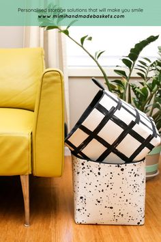 a yellow chair sitting next to a black and white box on top of a wooden floor