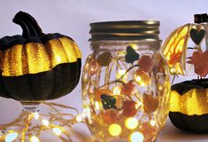 three pumpkins are sitting next to each other in glass jars with lights on them