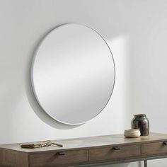 a round mirror on the wall above a dresser