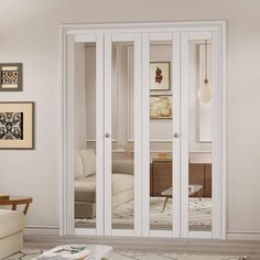 an empty living room with white furniture and pictures on the wall behind glass sliding doors