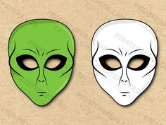 two green and white alien masks with black eyes on cardboard paper, one is facing the camera