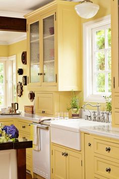 a kitchen with yellow cabinets and white counter tops