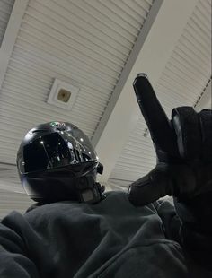 a person wearing a motorcycle helmet and holding their hand up in the air while sitting down