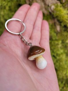 a hand holding a tiny mushroom keychain in it's palm