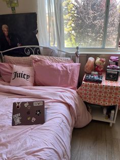 a bed with pink sheets and pillows in front of a window