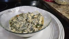 a glass bowl filled with food on top of a white plate next to a stove