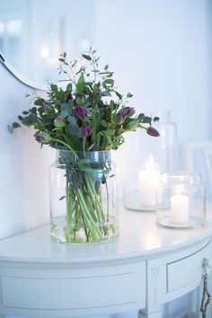 a vase filled with flowers sitting on top of a white table next to a mirror