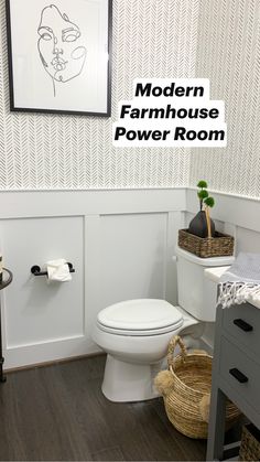 a white toilet sitting in a bathroom next to a wooden floor and wall mounted art